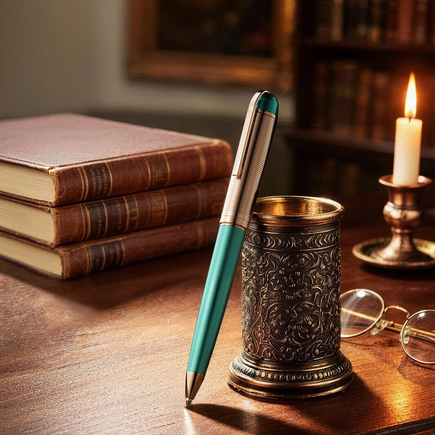 Teal pen with decorative holder on a wooden desk with books and candle in the background