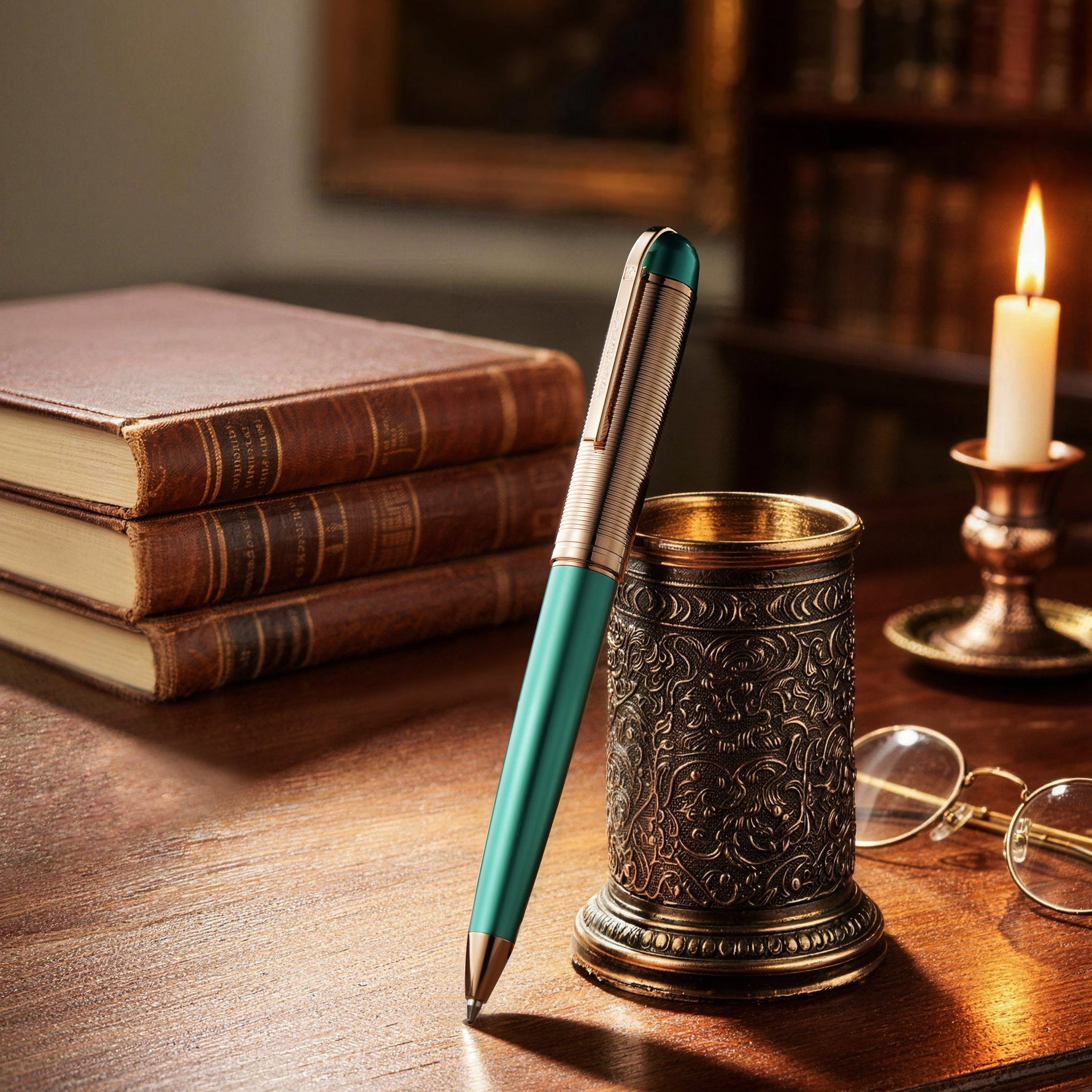 Teal pen with decorative holder on a wooden desk with books and candle in the background